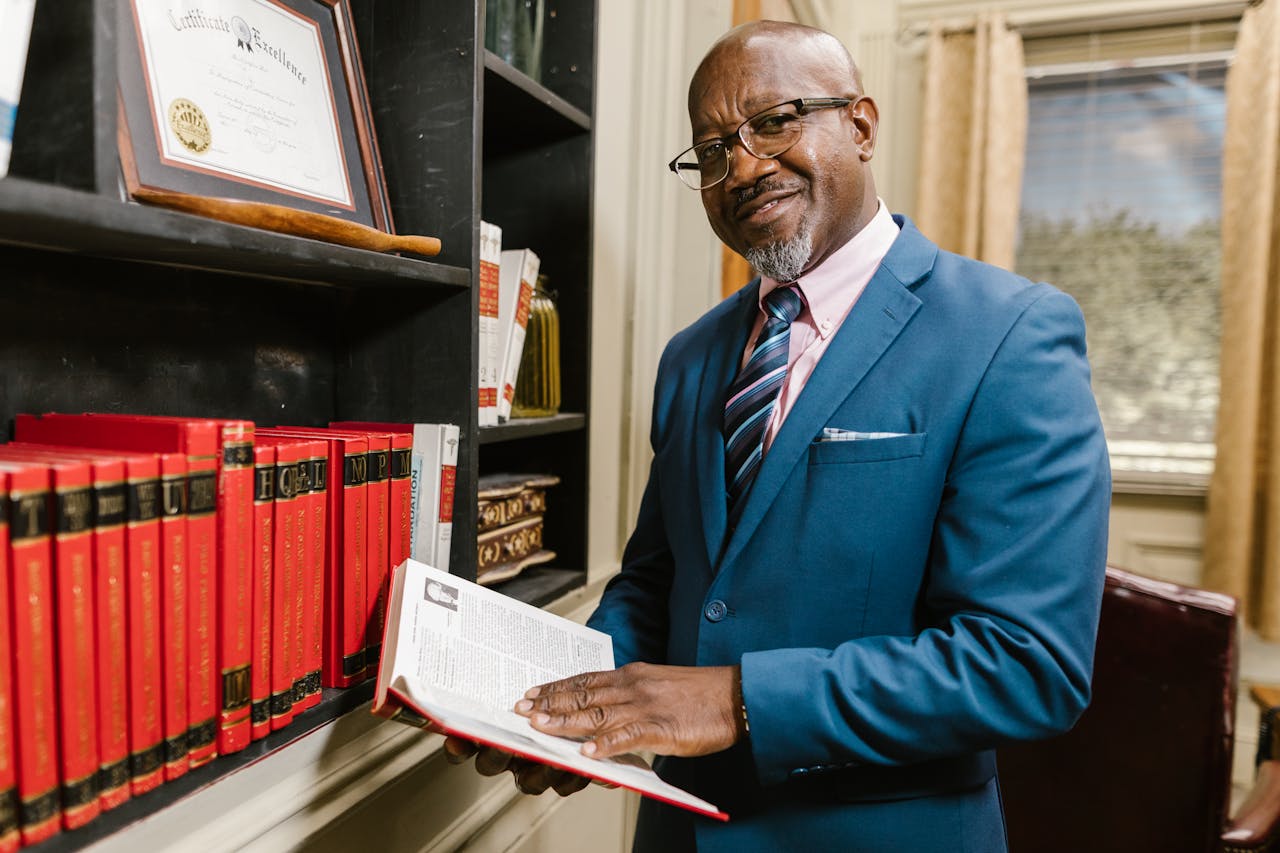 Crafting Captivating Headlines: Your awesome post title goes here Professional lawyer in formal attire holding a book, smiling in an office setting surrounded by law books.