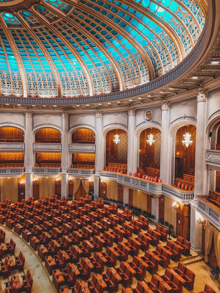 About Majestic view of an ornate parliamentary chamber with a striking turquoise dome and plush seating.